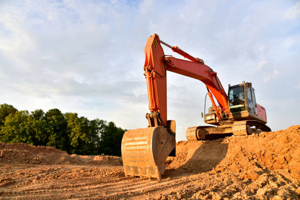 Excavator dig sand at the open-pit. Heavy machinery working in the mining quarry. Digging and excavation operations. View on the mountains with yellow sand for local civil work
